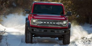 A red 2025 Ford Bronco driving through snow, utilizing Ford AdvanceTrac to stay on the road