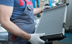A mechanic holding a radiator - Cooling System and Radiator FAQ: How Your Ford's Cooling System Keeps Your Engine Running Smoothly