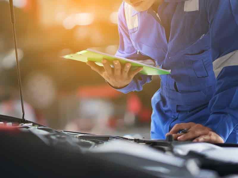 Atchinson Ford in Belleville MI technician leaning on vehicle to inspect an engine